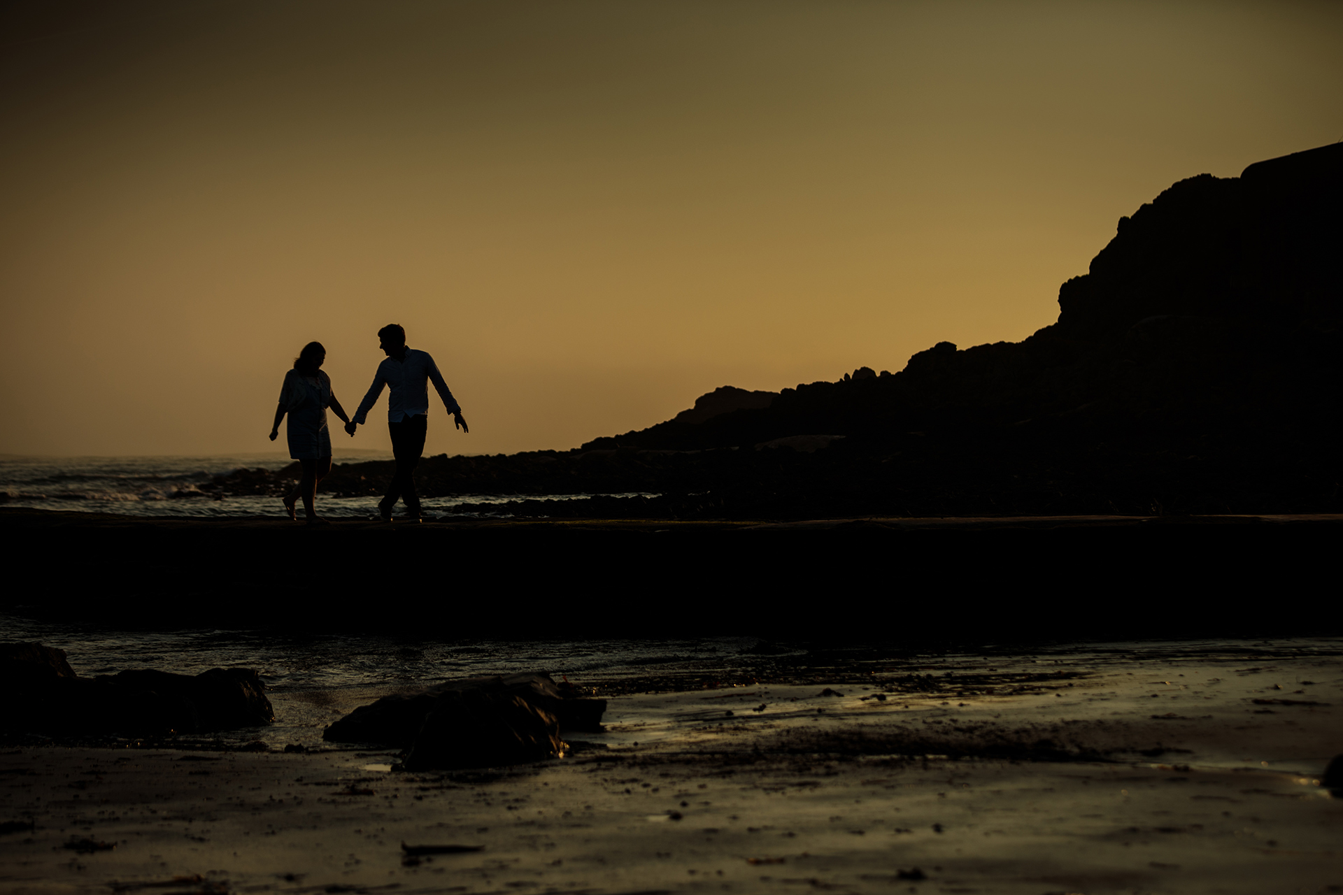 Couple hold hands at sunset at L'Etacq Jersey, CI