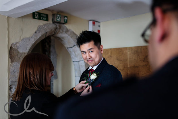 the best man has his corsage attached at Lympne Castle