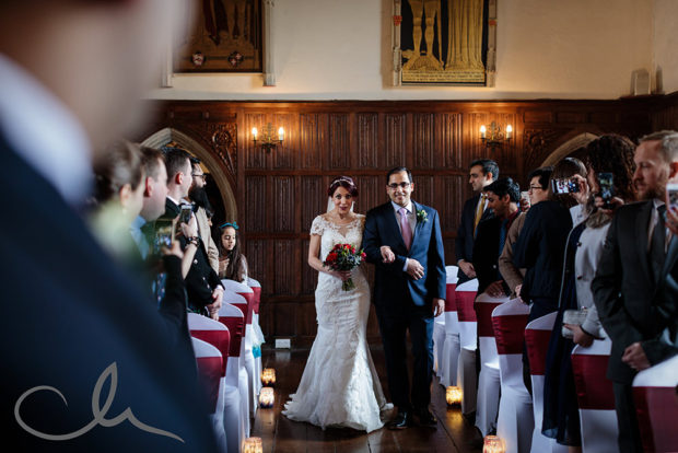 The bride and her brother walk up the aisle to meet her future husband at Lympne Castle