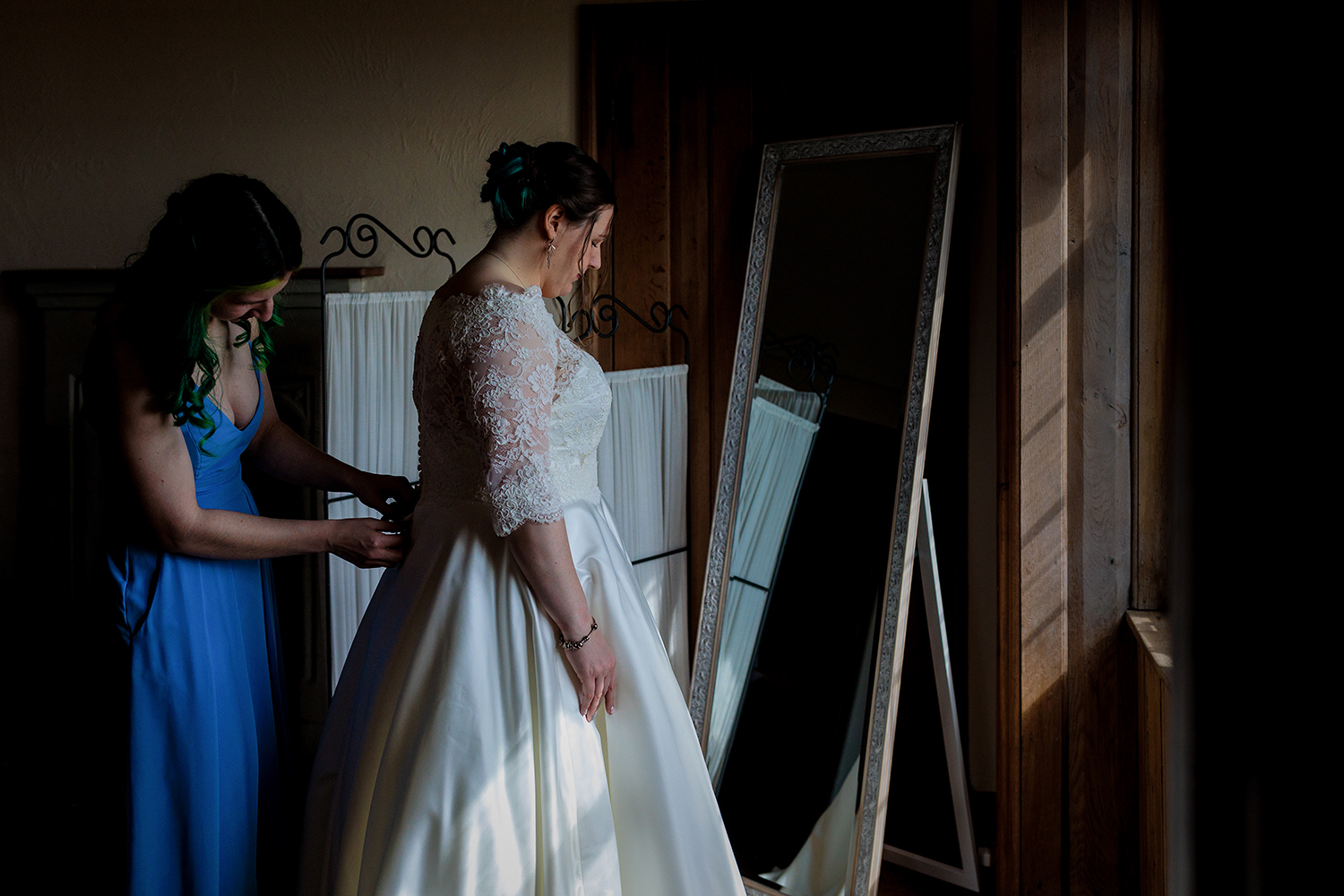 Bridal prep at Lympne Castle -the bridesmaid laces up the brides dress