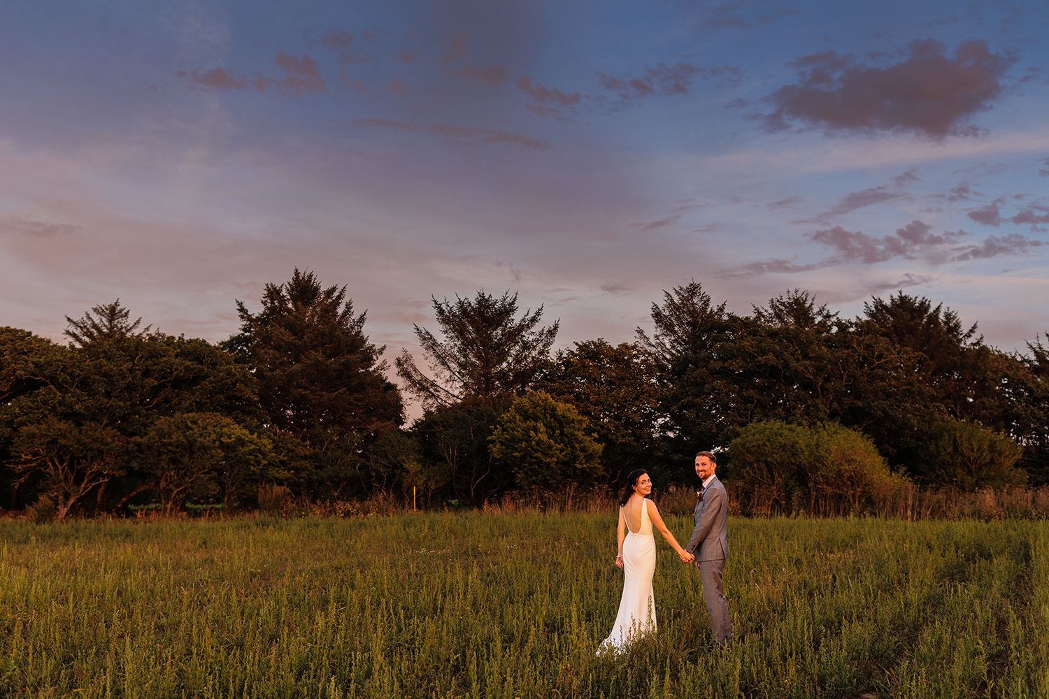 The Bride and groom walk hand in hand at sunset time at La Mare Wine Estate Jersey