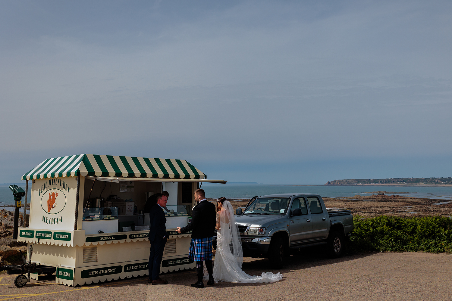 The bride and groom purchase Jersey Ice cream at Corbiere Lighthouse, St Brelade, Jersey CI