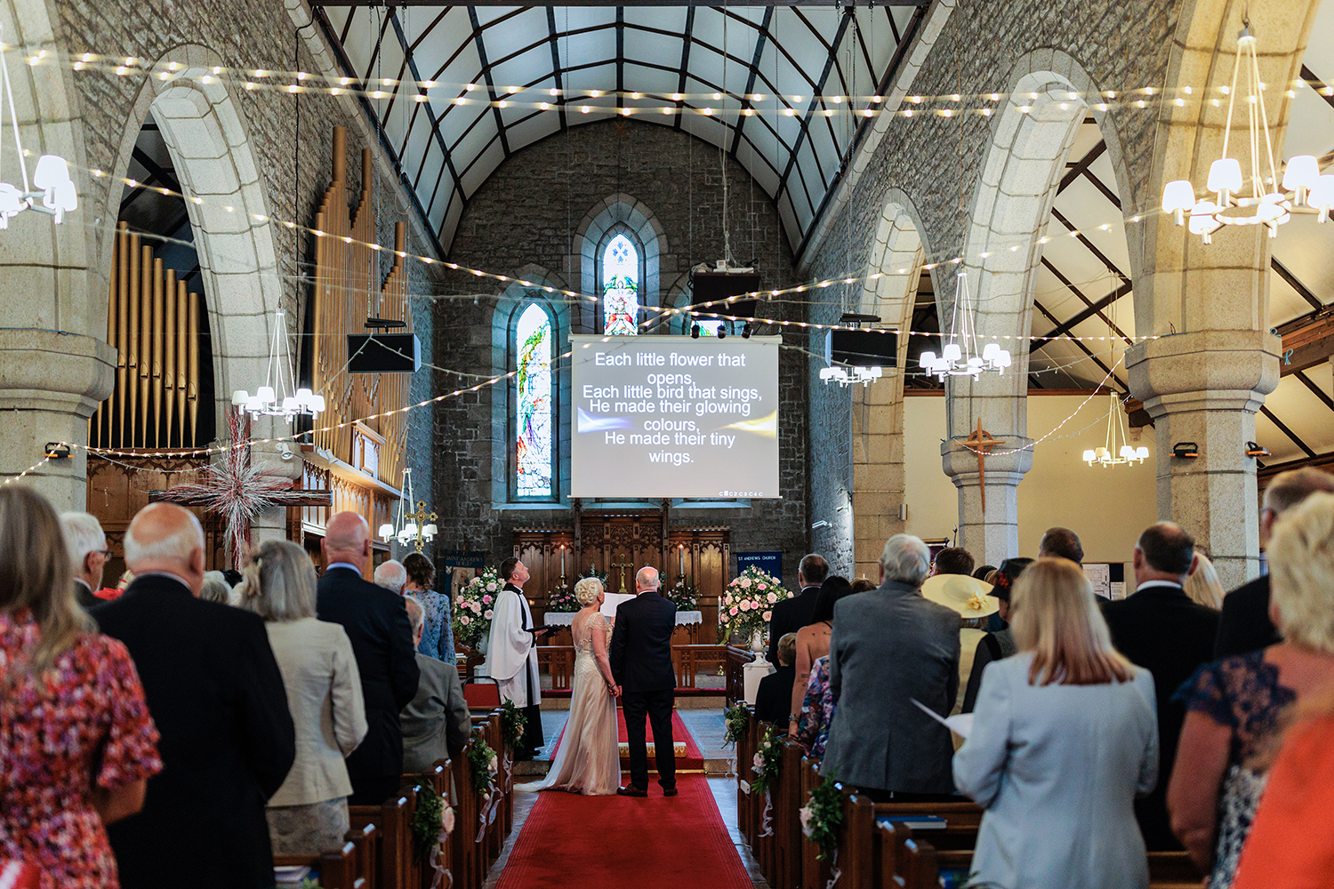 The bride and groom and congregation sing hymns at their wedding ceremony at St Andrew's Church, St Helier Jersey CI