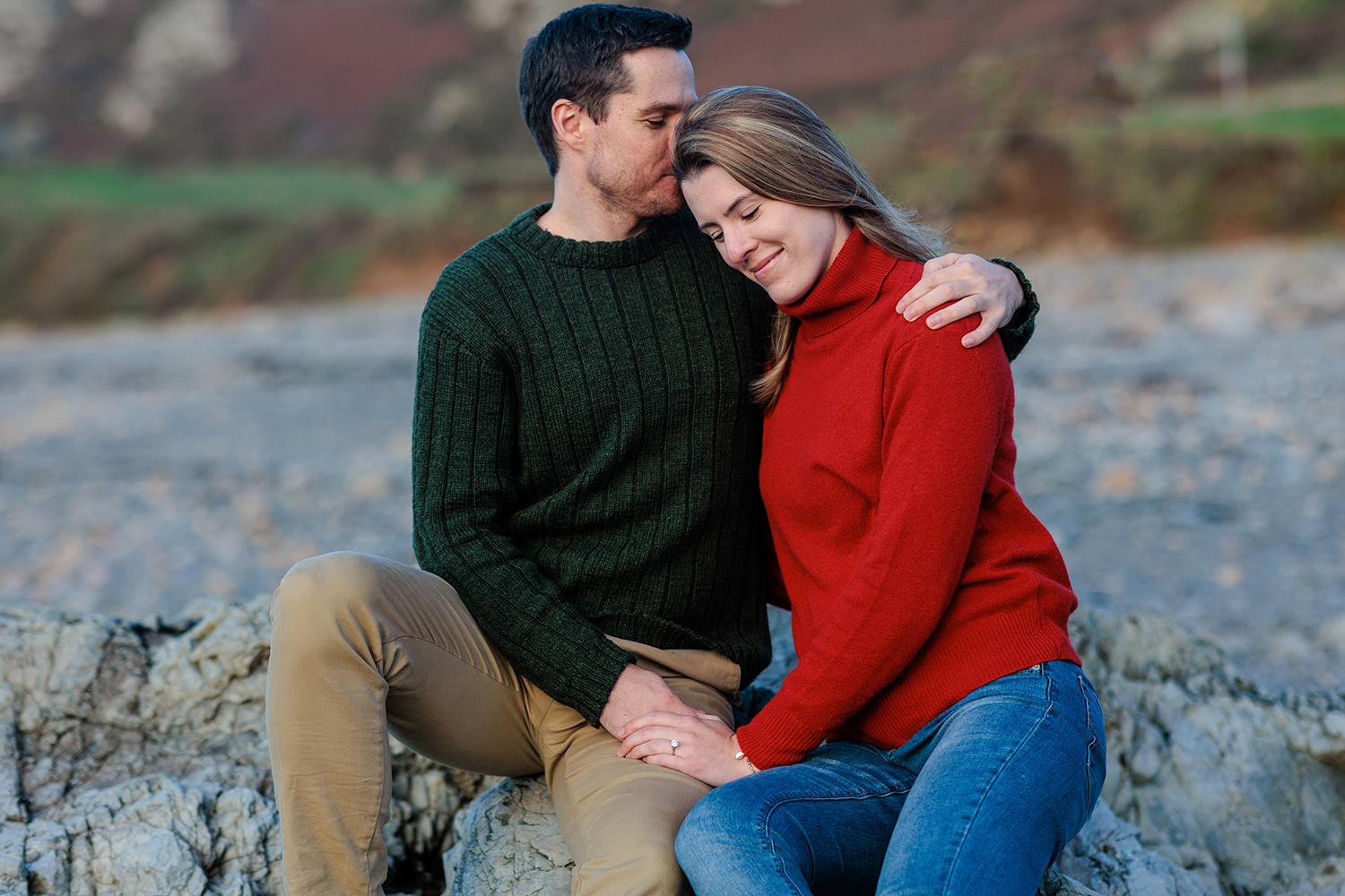 The happy couple cuddle up on the rocks at L'Étacq for the Jersey Engagement Photography