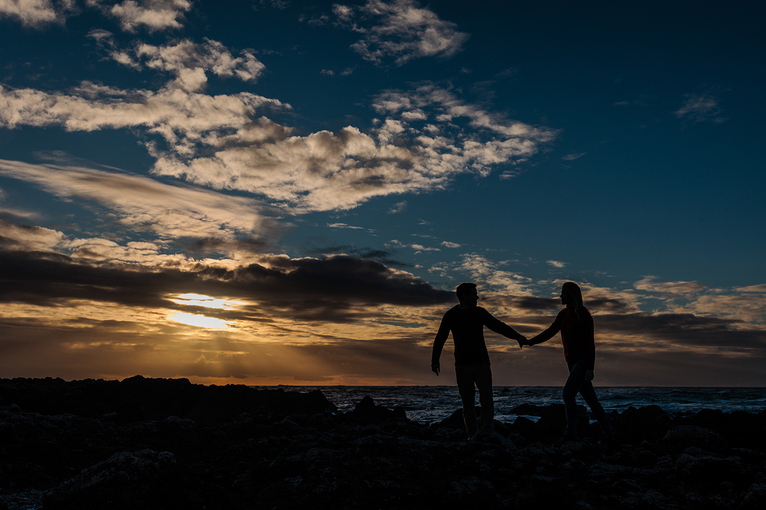 the couple are silhouetted by the sunset at St Ouens Bay, Jersey